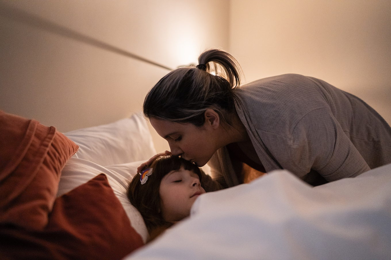 Mother putting daughter to sleep at home