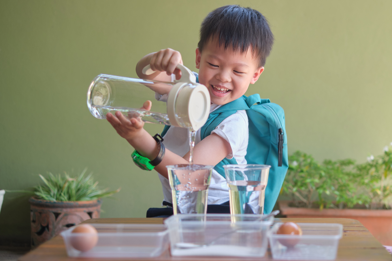 Happy Asian kid studying science, pouring water to do fun and easy Floating Egg Science Experiment
