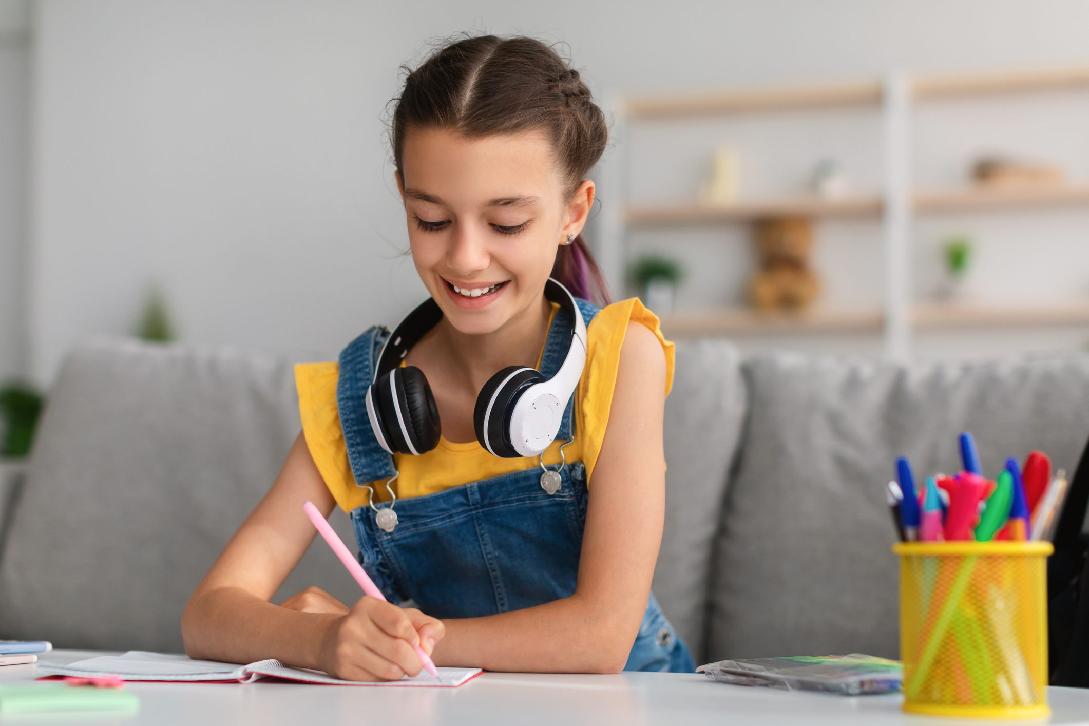Smiling girl sitting at table, writing in notebook