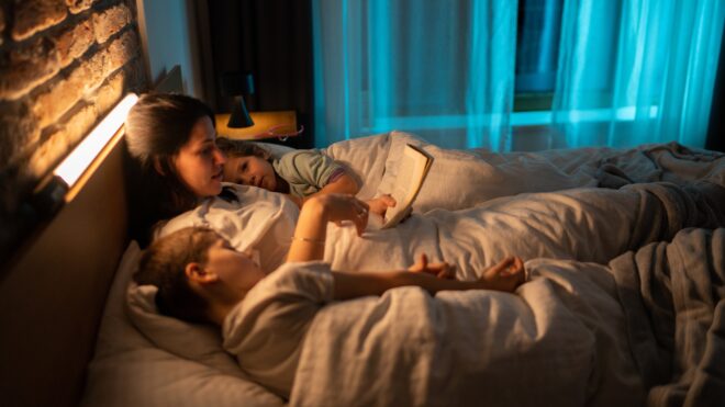 woman reading bed with kids
