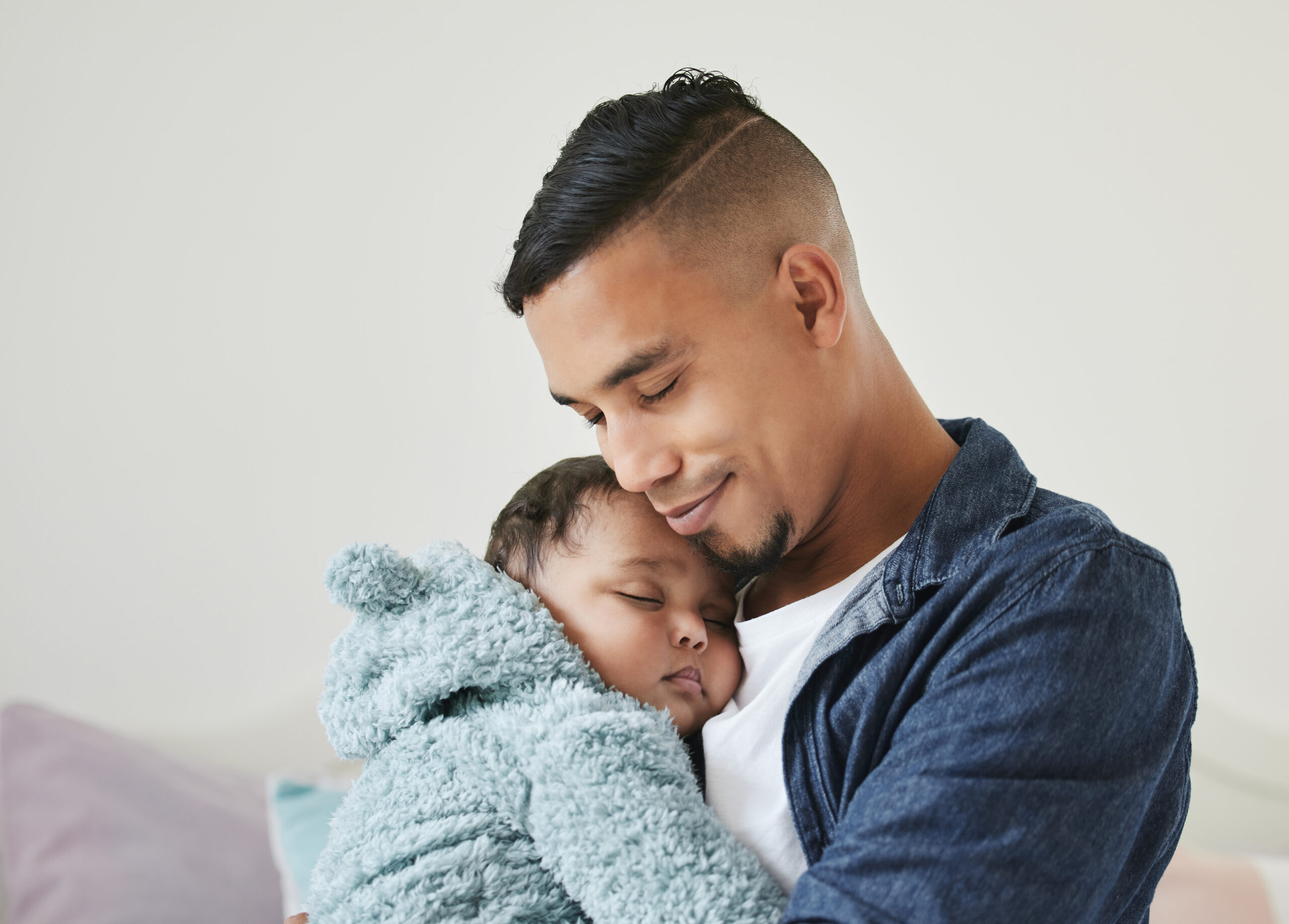 Shot of a young father embracing his baby at home