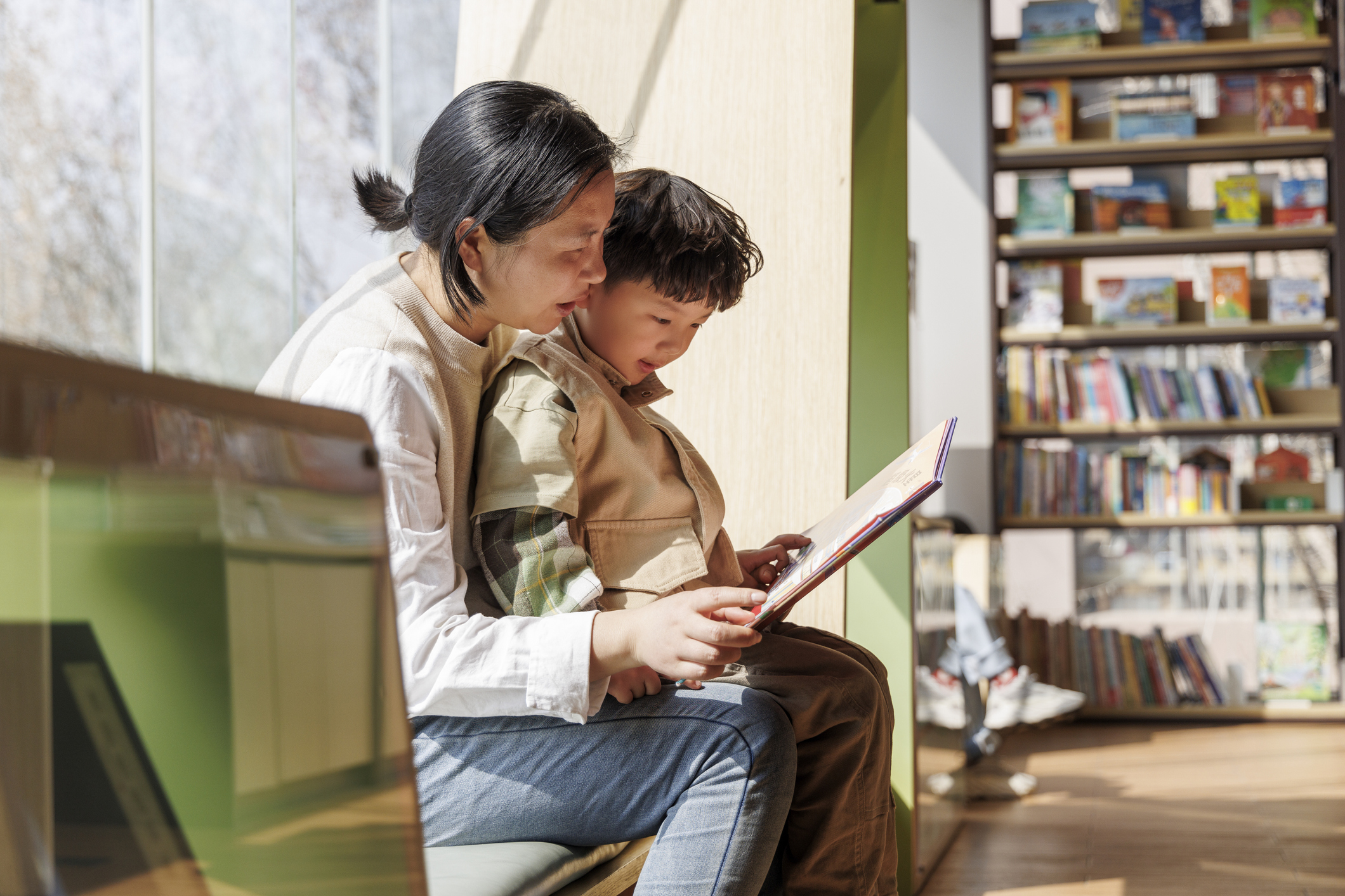 mother and son reading book by the window