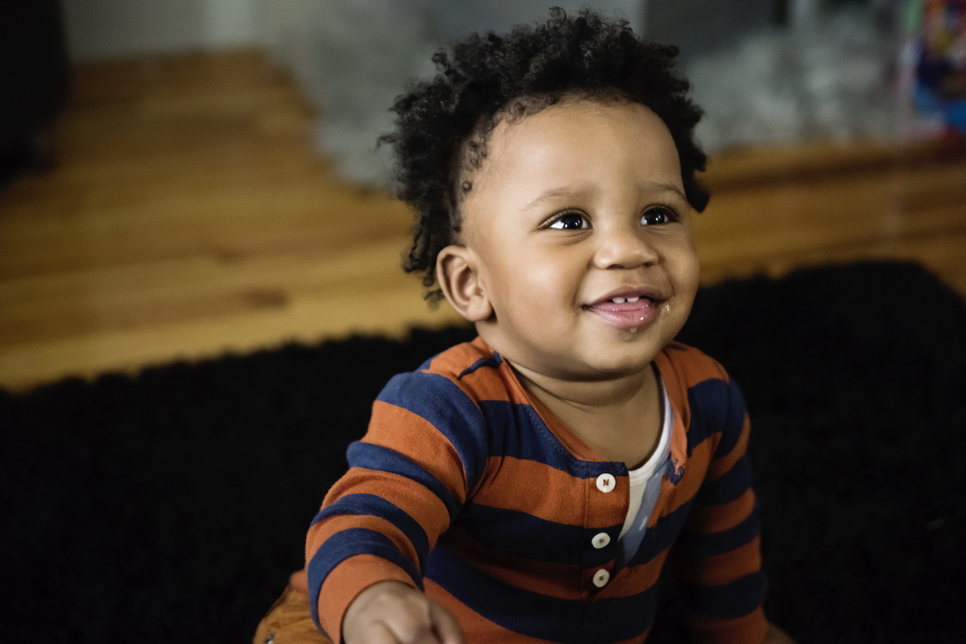 Playful baby boy with striped shirt at home.