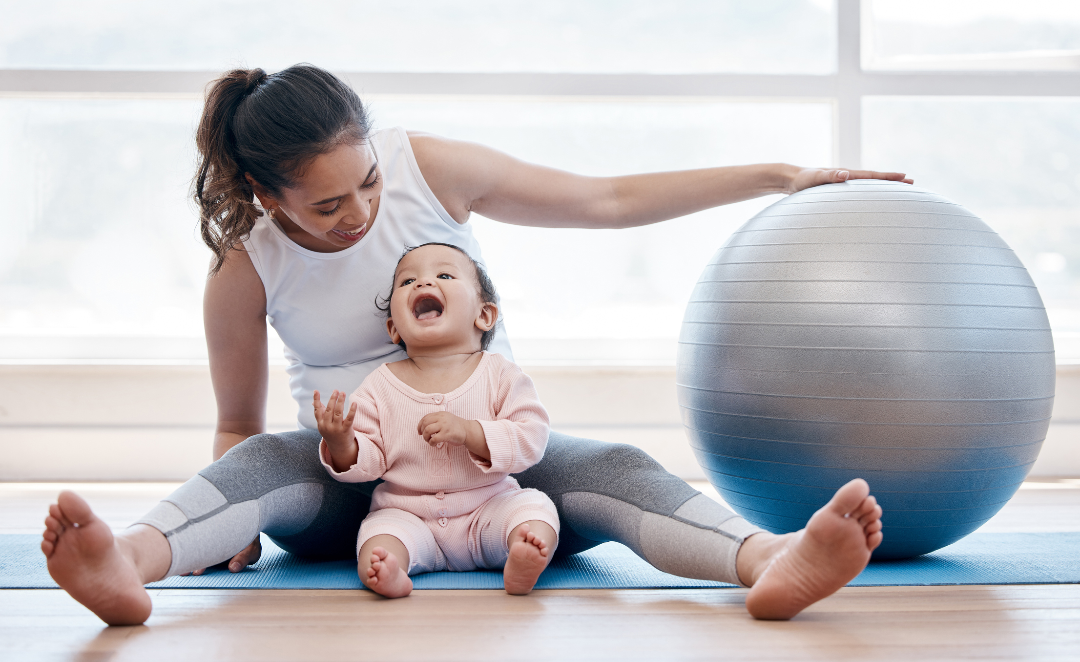 Shot of a young mother exercising with her baby girl at home