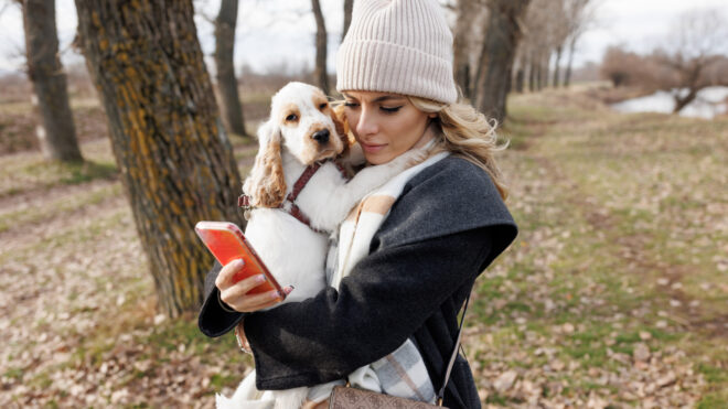 woman holding dog looking at phone