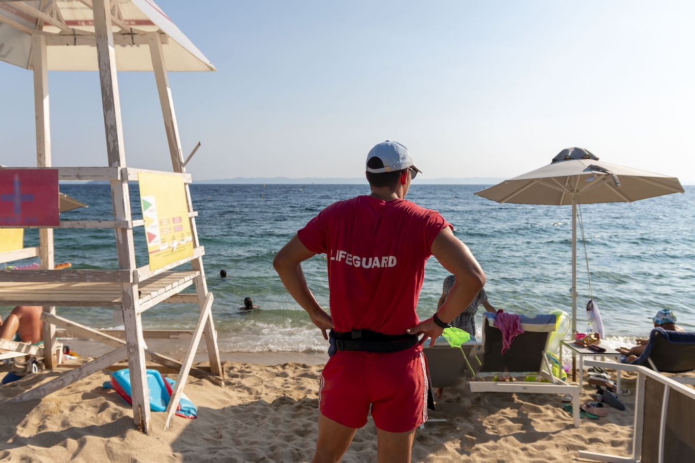 Back view of a young male lifeguard on the beach. Summer vacation