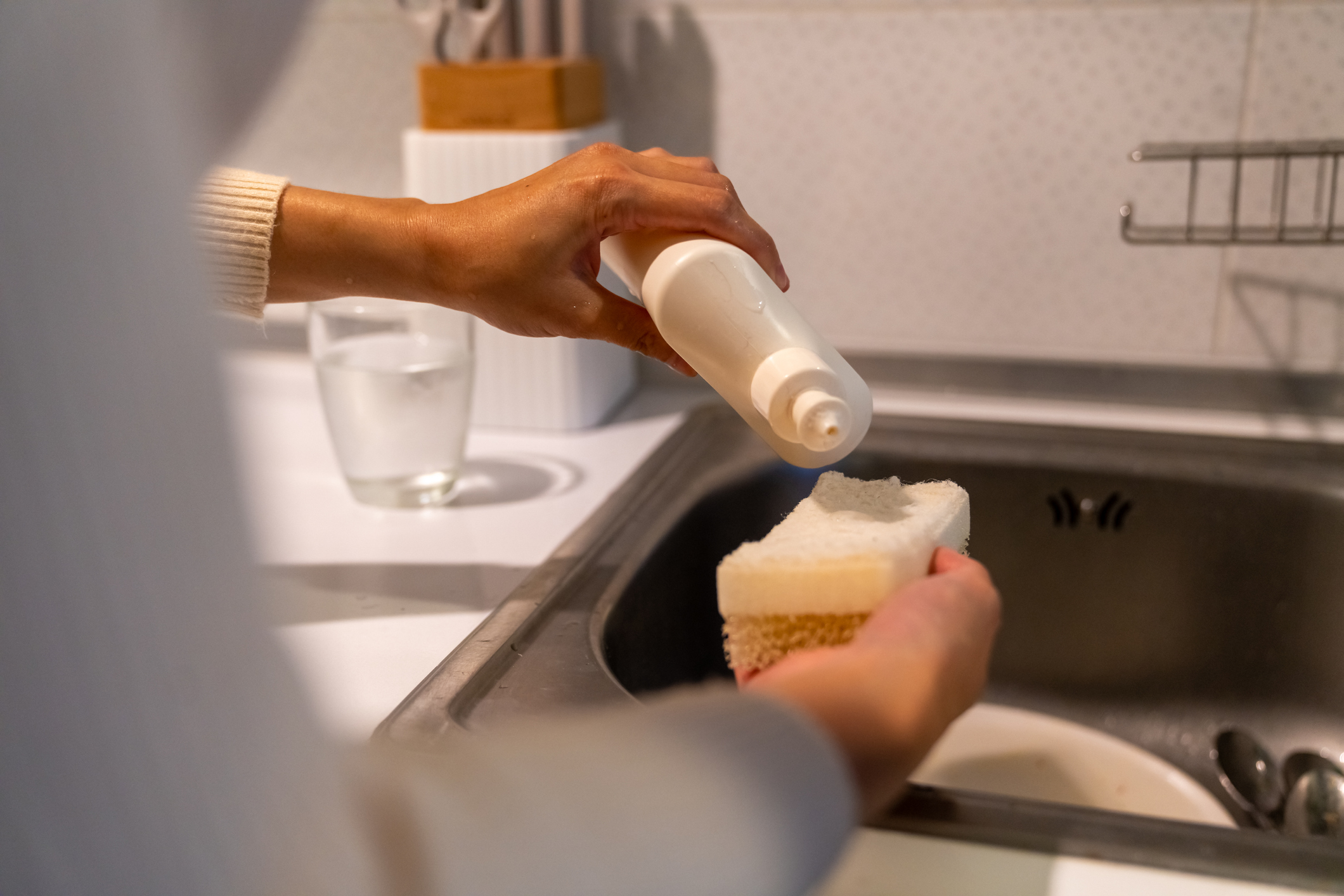 Young Asian woman washing dishes in the sink at apartment at night.