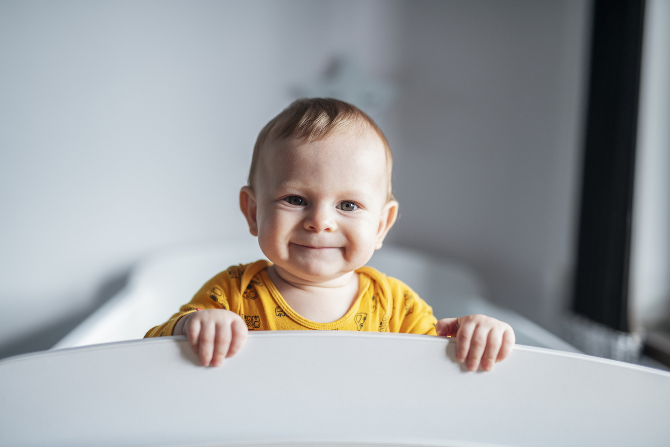 Portrait of cute little boy peeking through his crib.