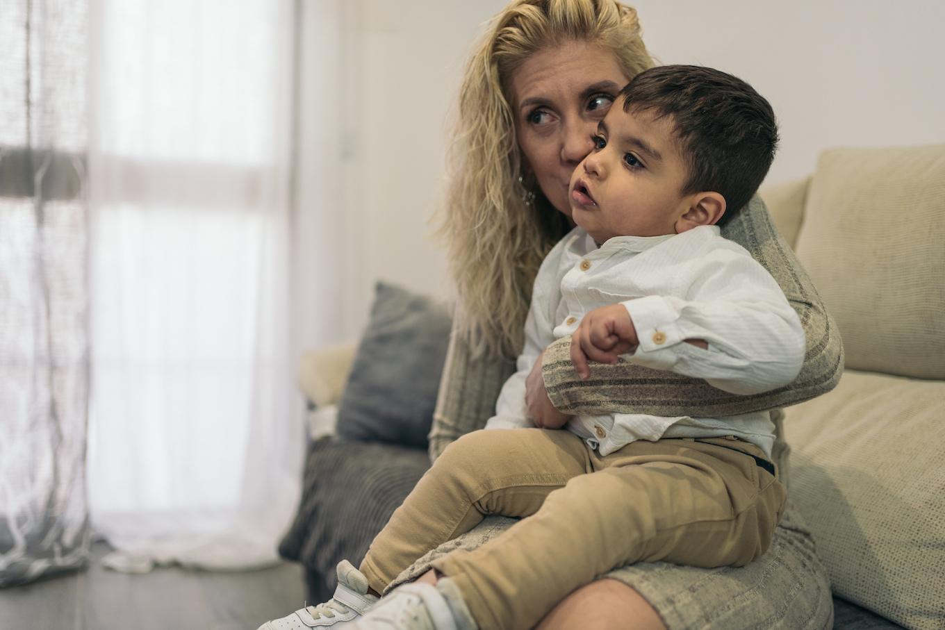 Middle-aged blonde woman sitting on her lap her young son with special needs because he is a person with a disability.