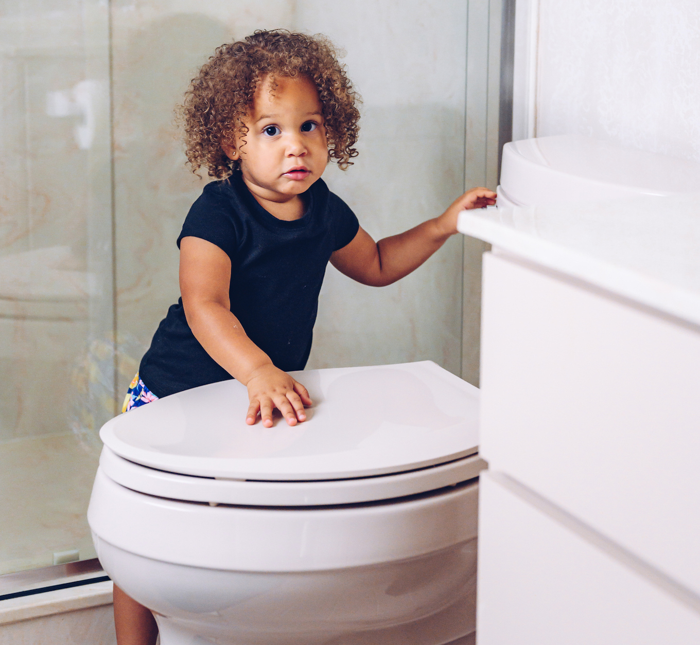 Mixed race toddler girl in the bathroom at home learning to use the toilet potty training