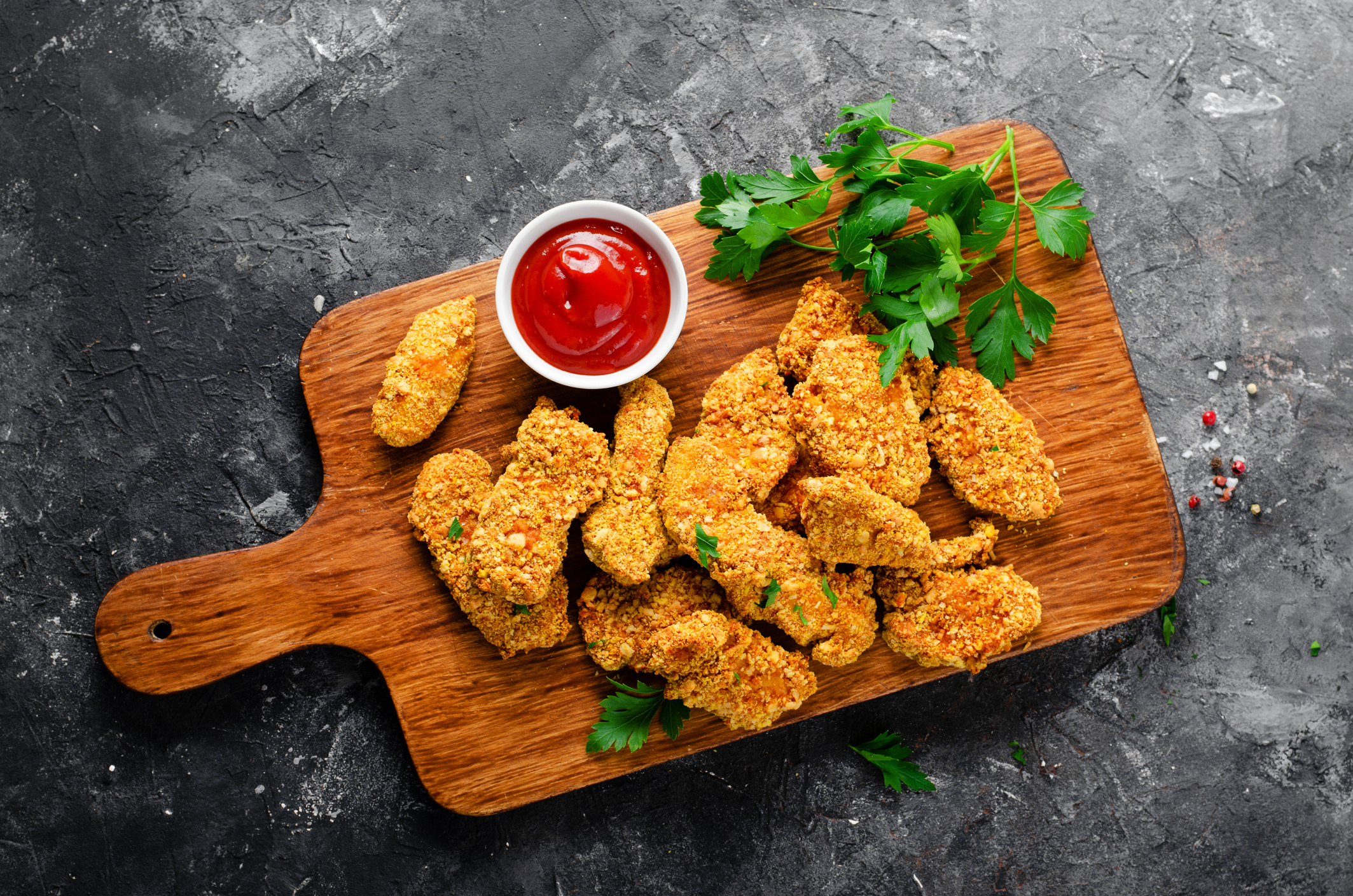 Delicious Crispy Fried Breaded Chicken Breast Strips with Ketchup on Dark Background