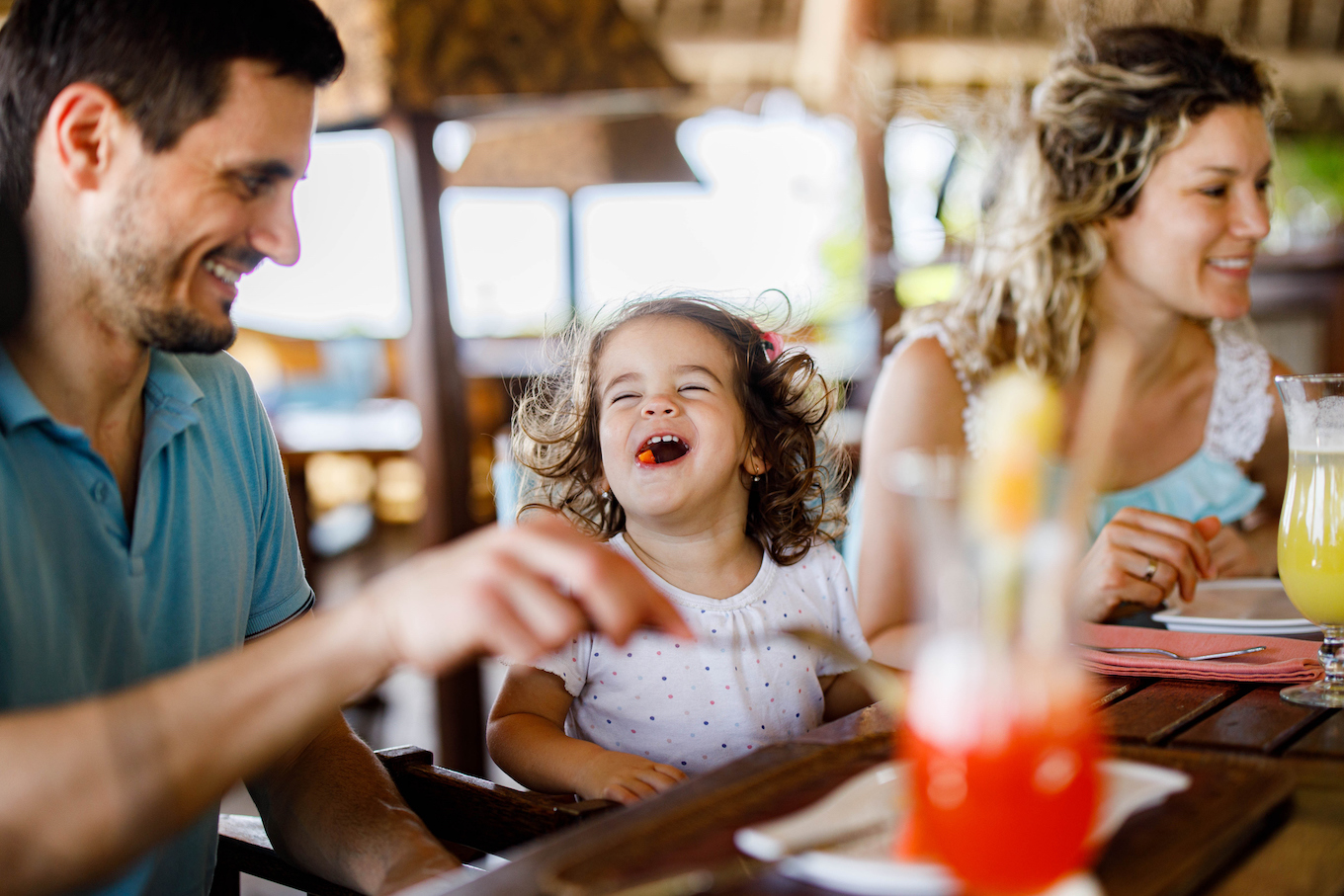 Happy girl enjoying with her parents during lunch in a restaurant.