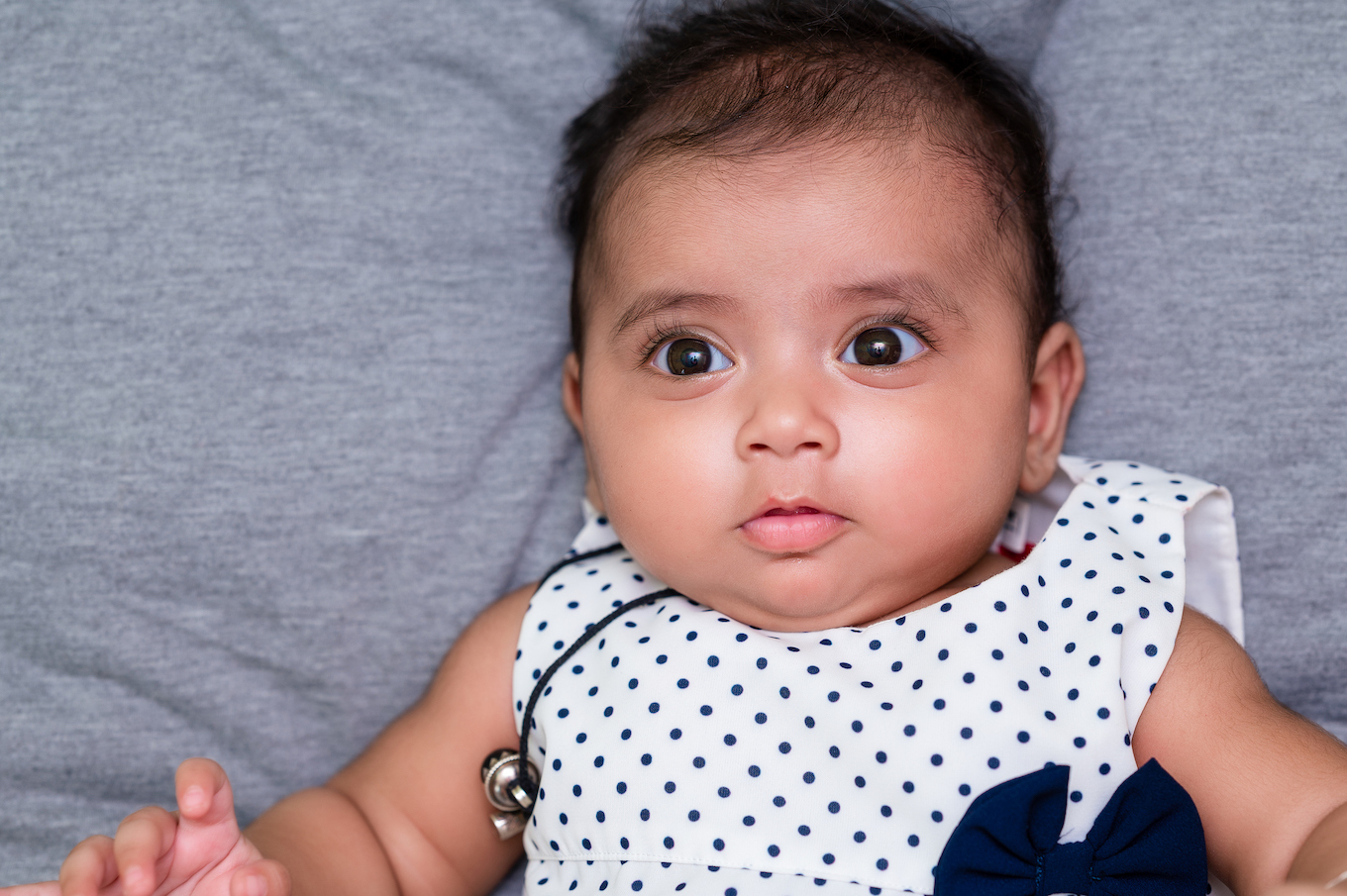 Newborn baby laying down on bed and looking at camera