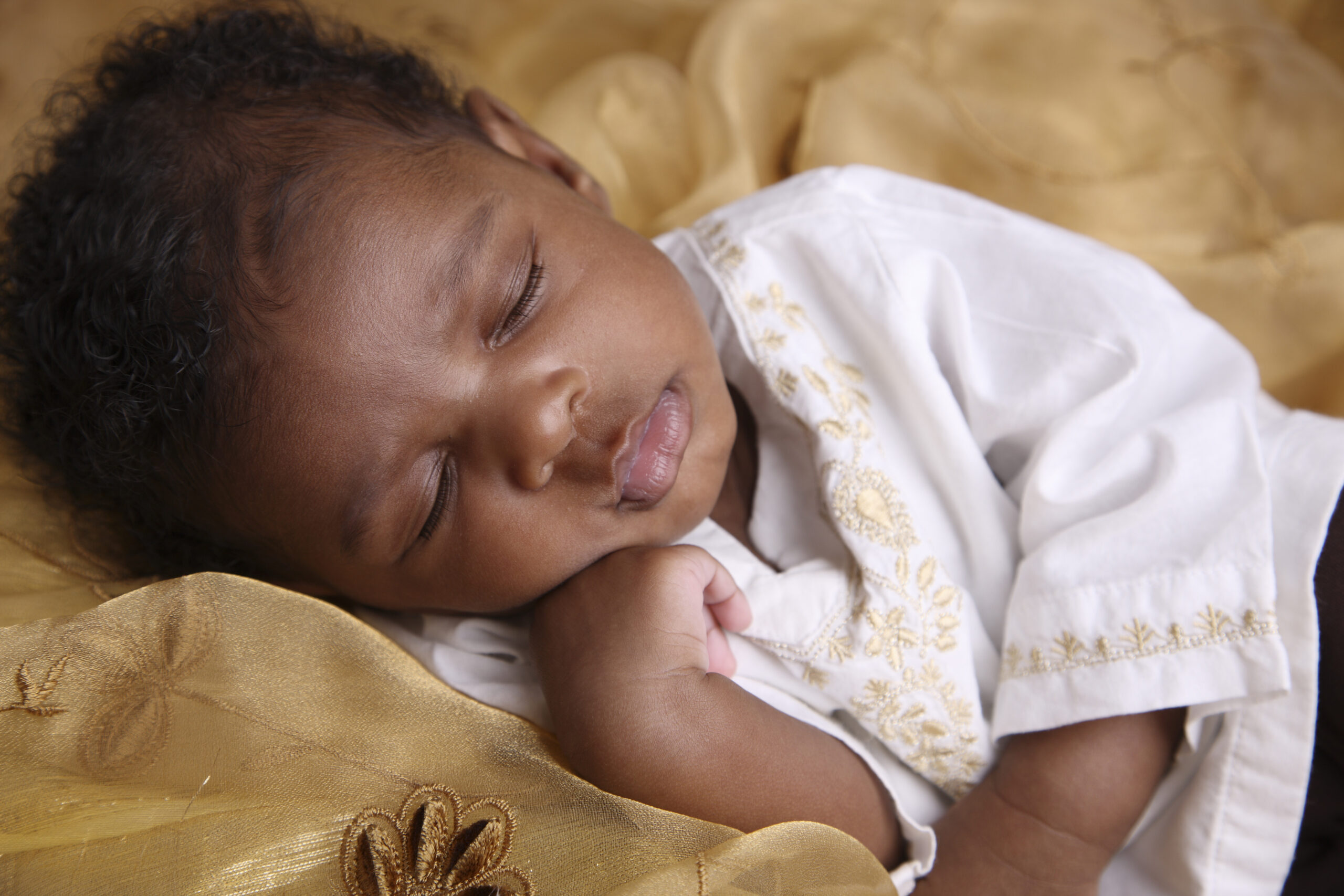 African-American baby with curly hair sleeping on a blanket
