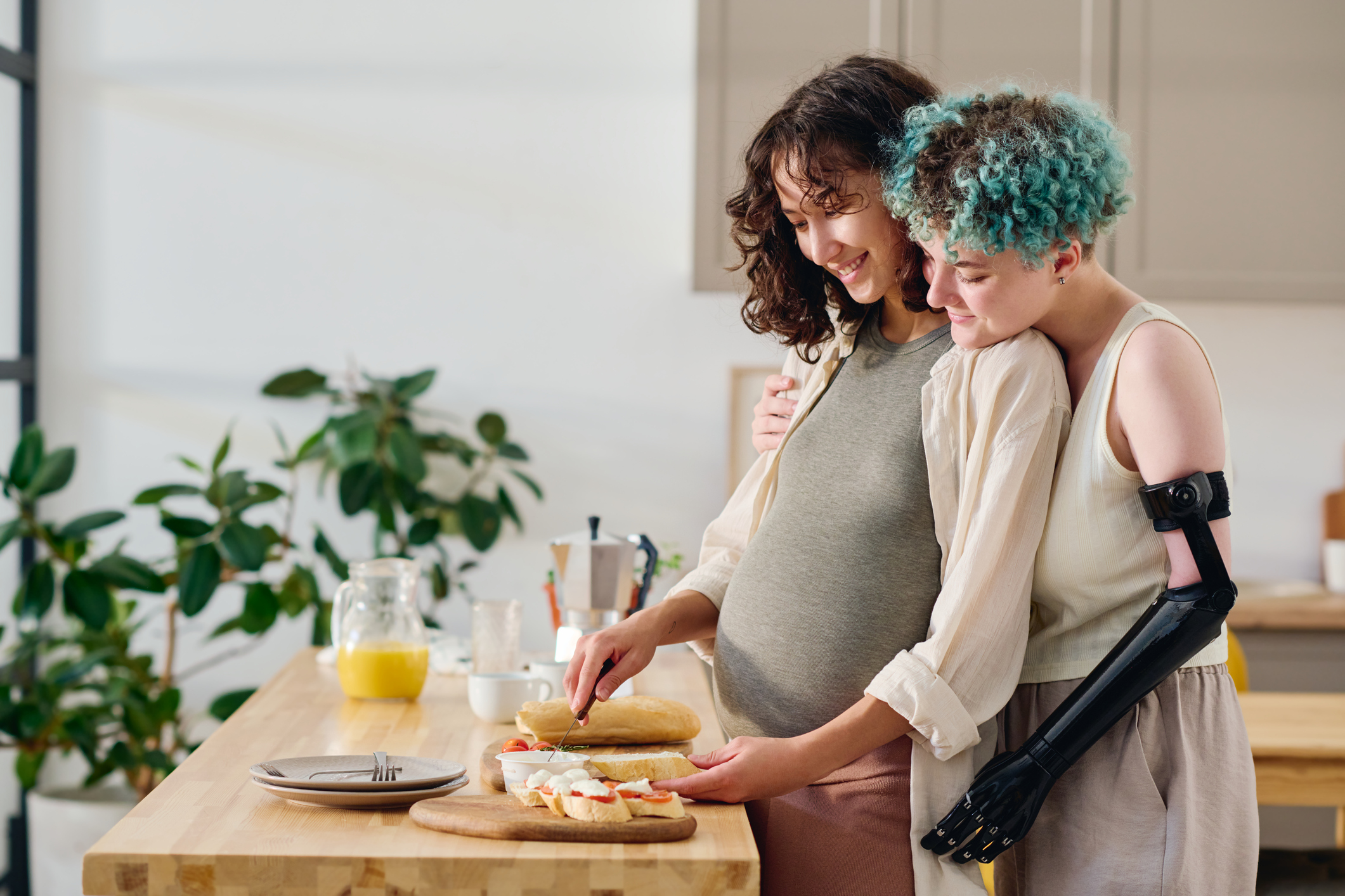 Side view of affectionate girl with disability embracing pregnant girlfriend
