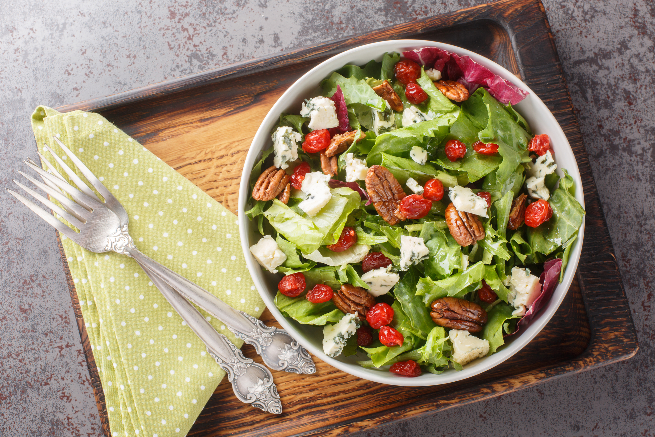 Michigan Cherry Salad with greens, blue cheese and pecan tossed with a vinaigrette dressing closeup on the plate. Horizontal top view