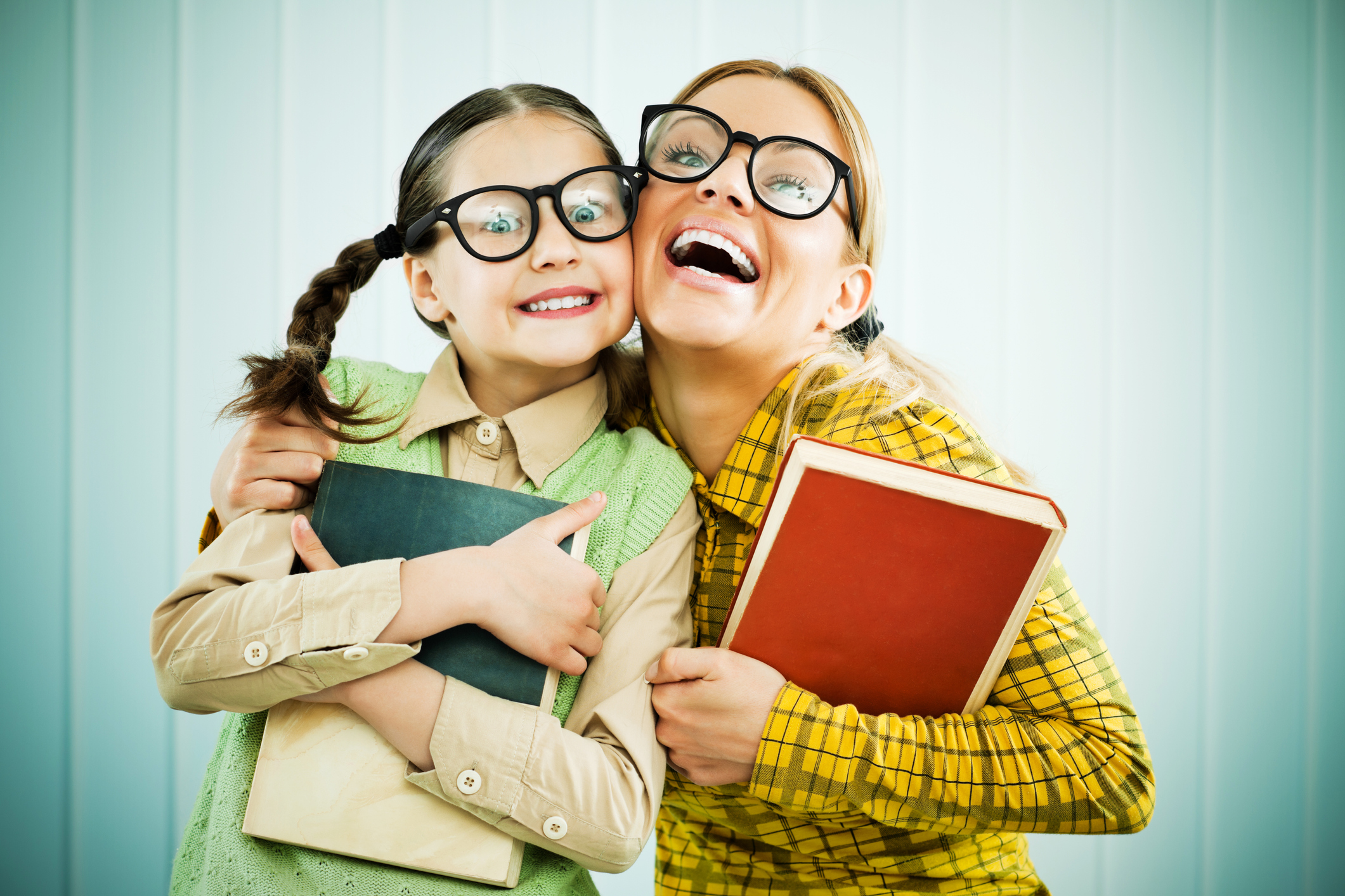 Embraced mother and daughter holding books.
