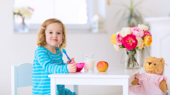 Girl sitting at a table eating breakfast