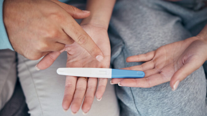 couple's hands and closeup of pregnancy test