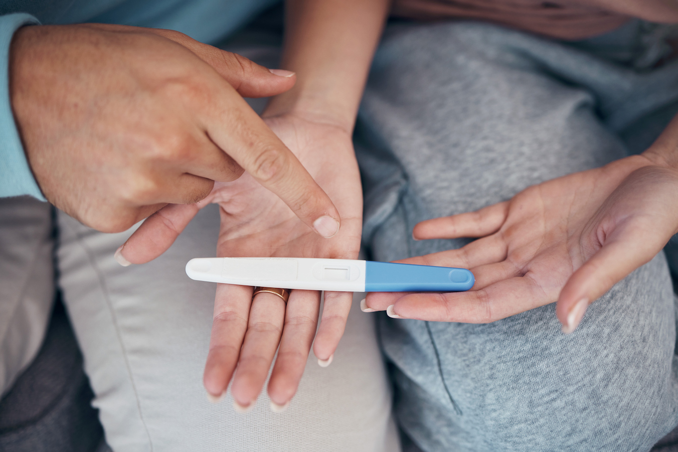 Hands, couple and closeup of pregnancy test, results and waiting for news together in home. Top view, kit and pregnant woman and man family planning for future maternity, ivf fertility and support