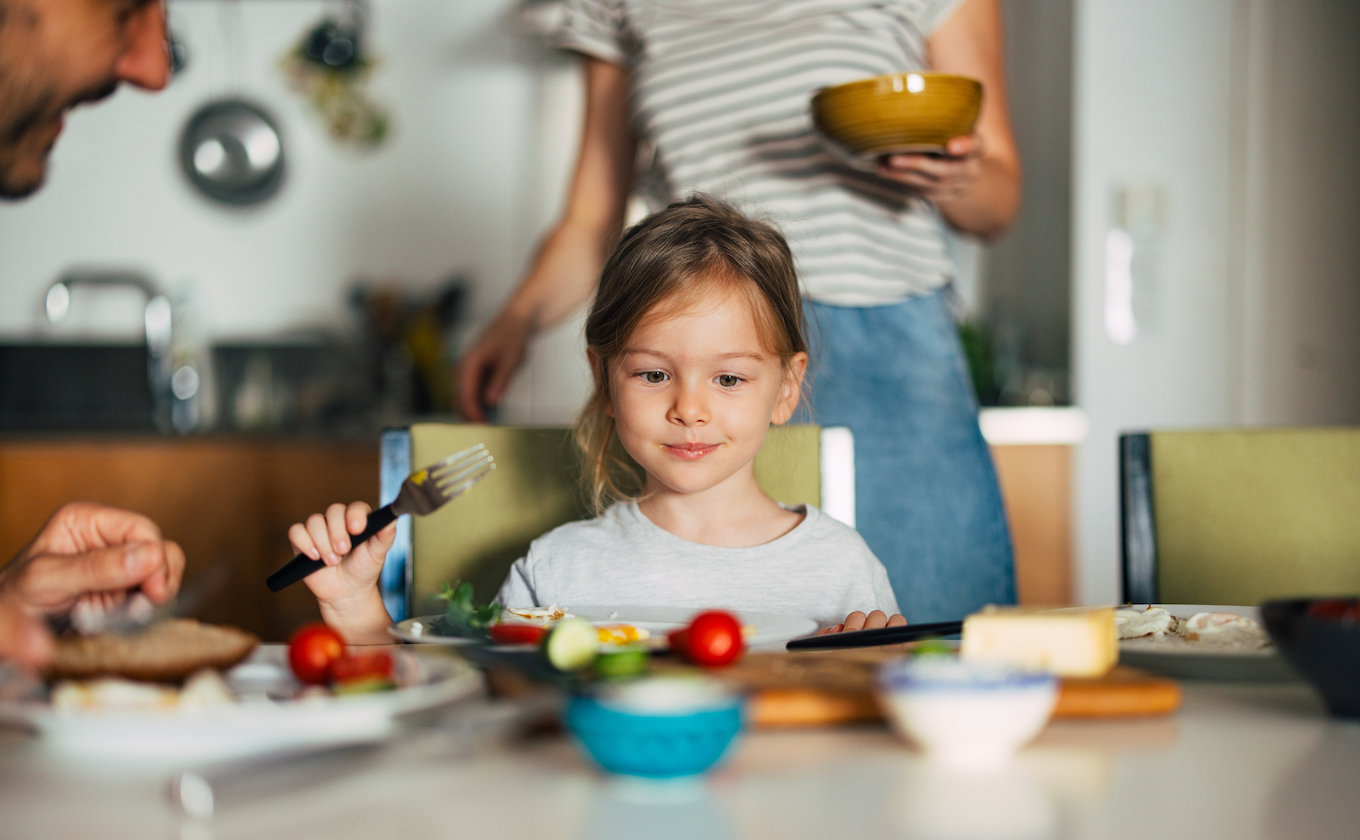 Close Up Photo Of A Little Girl Having Breakfast With Her Unrecognizable Family