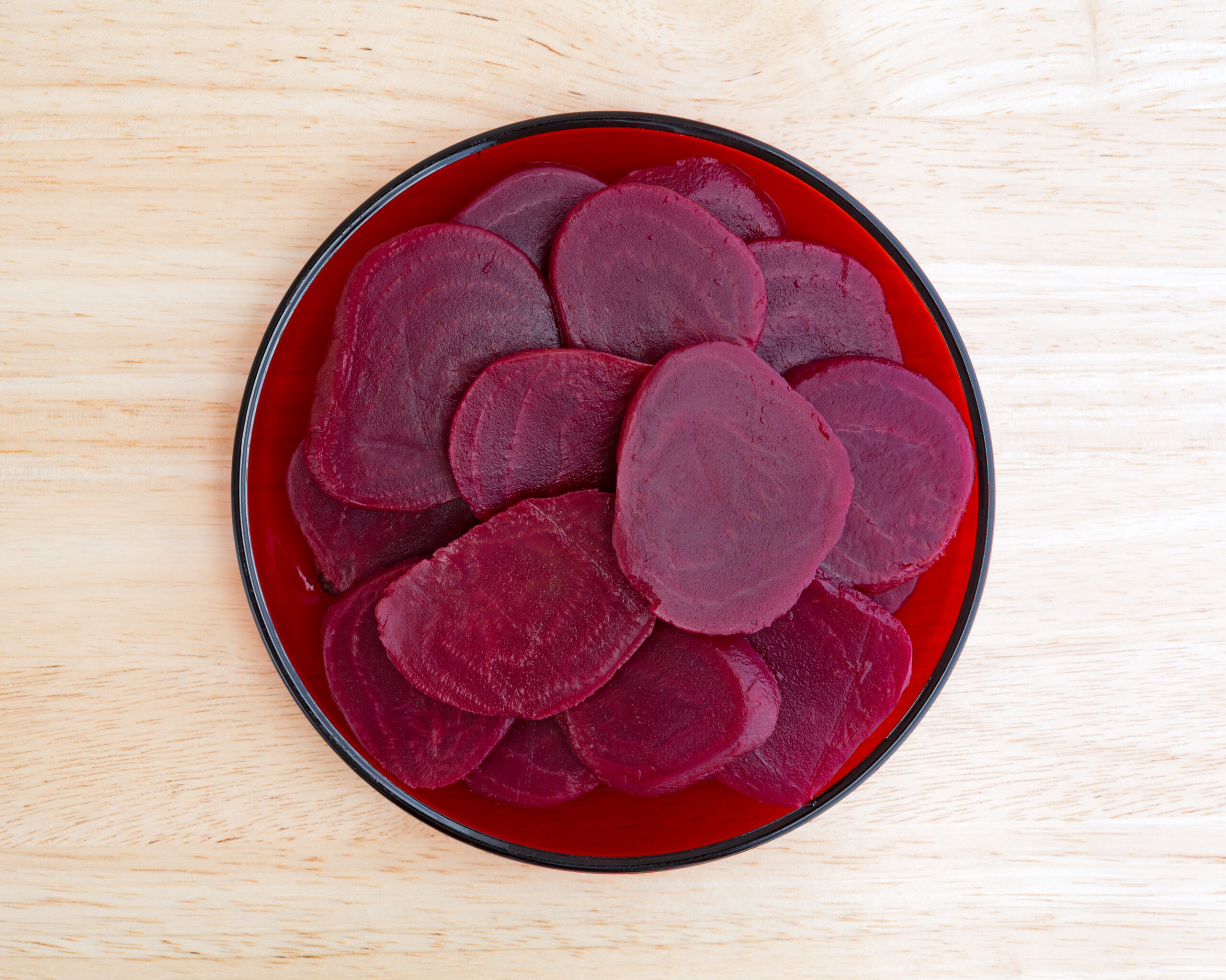 Sliced beets on a red plate atop table