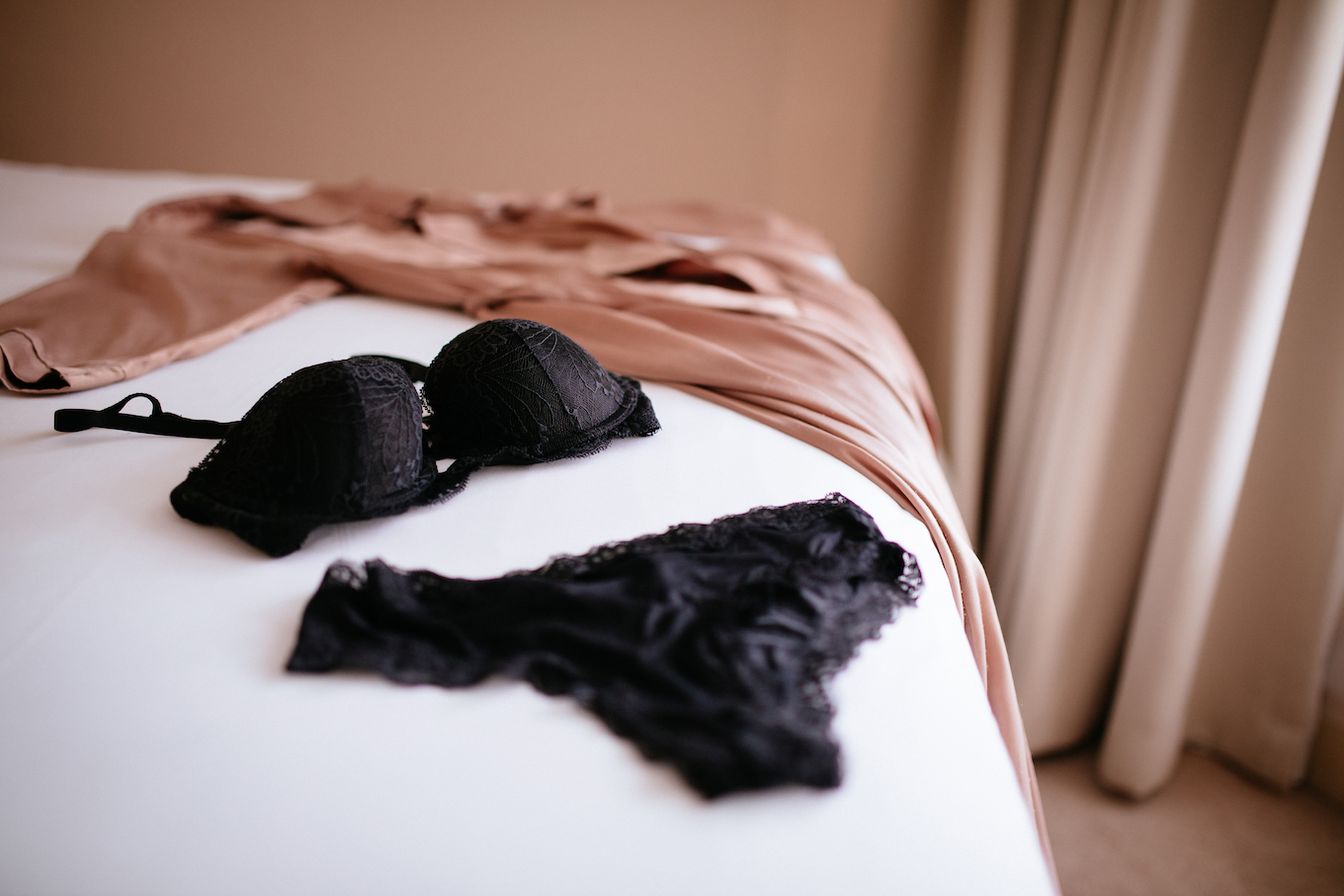 Lace lingerie and silk robe placed on bed