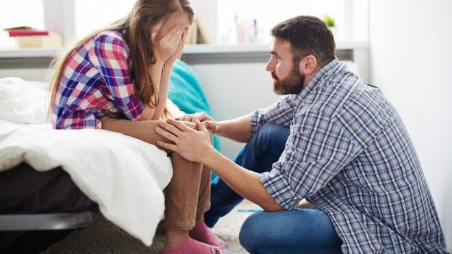 teen girl upset and dad consoling her