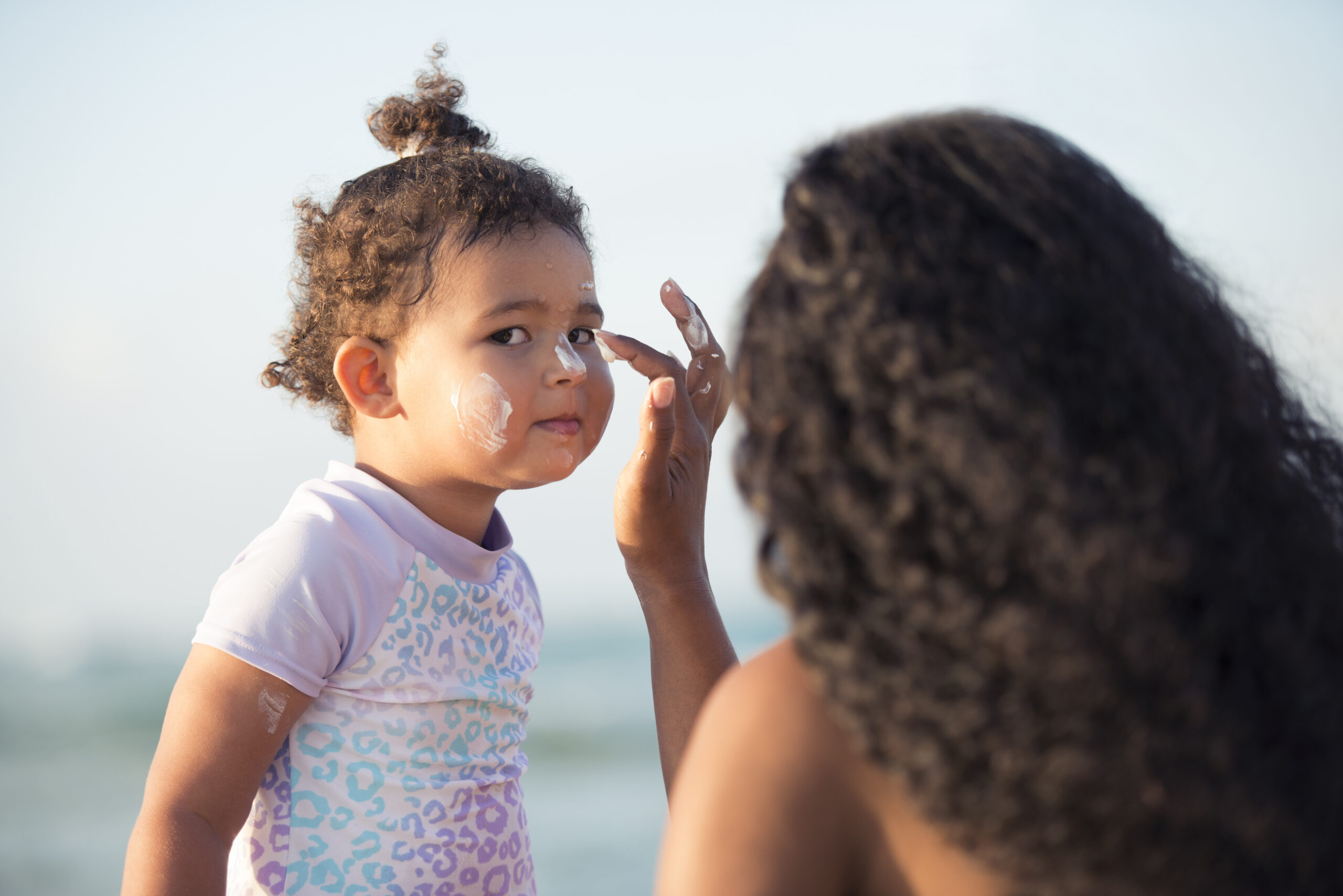 Mother applying sun protection on her baby girl's face.