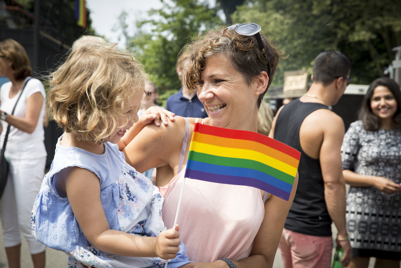 young mother with her daughter waving a rainbow flag