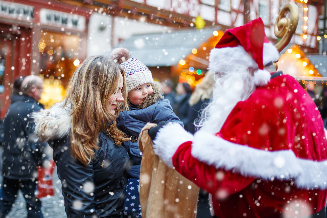 Little toddler girl with mother on Christmas market.
