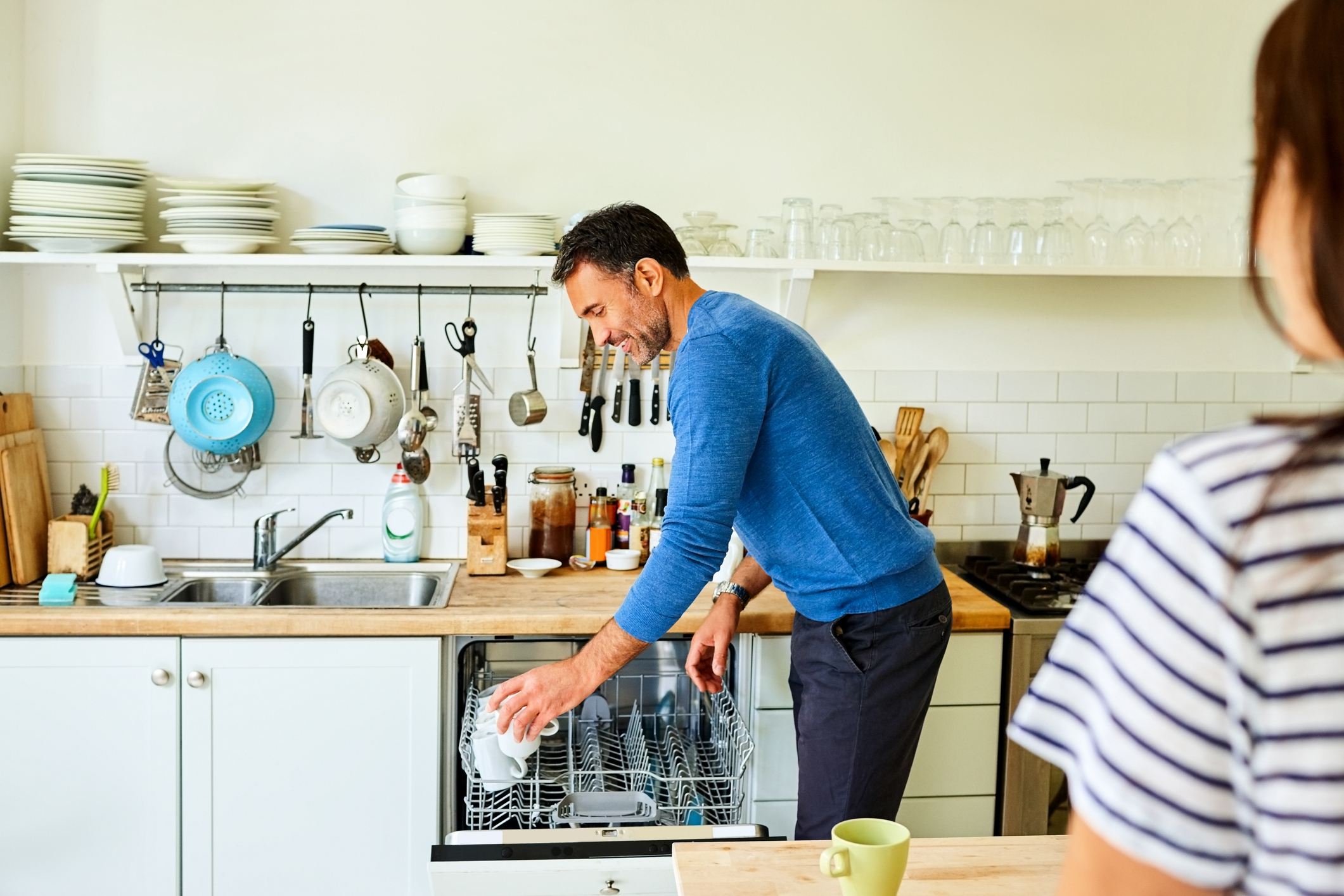 Mature man putting coffee mugs in dishwasher