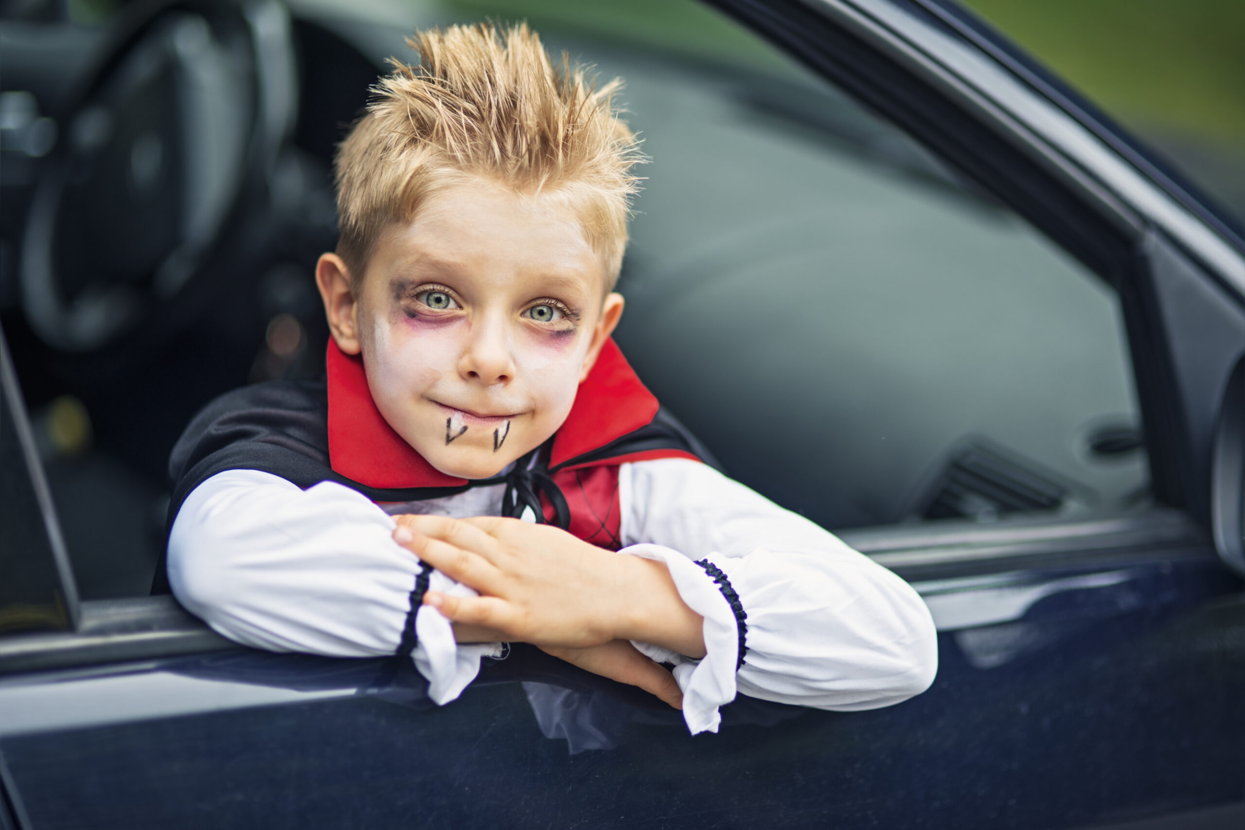 Little halloween boy smiling out of the car