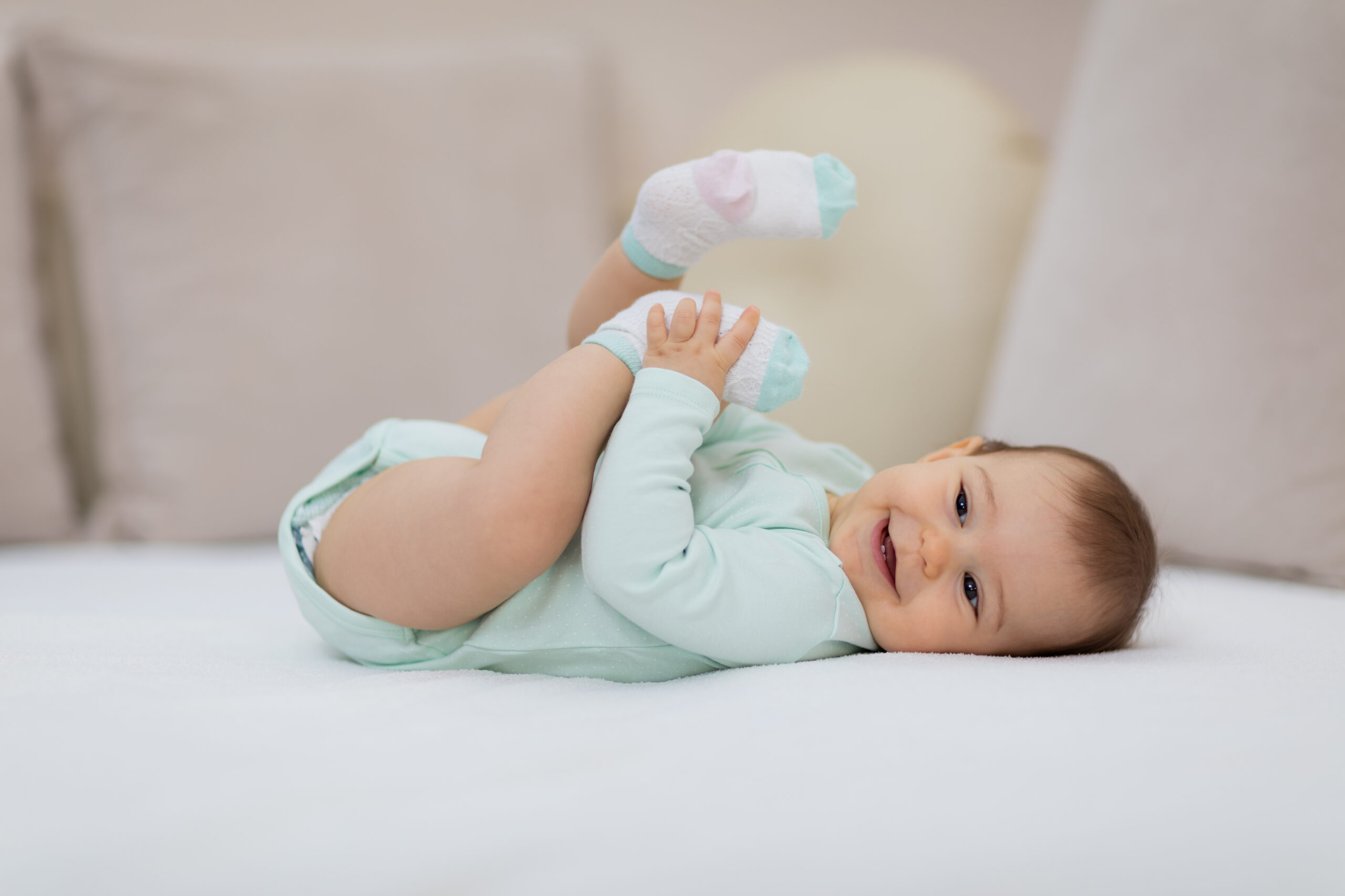 Playful baby lying down in bed