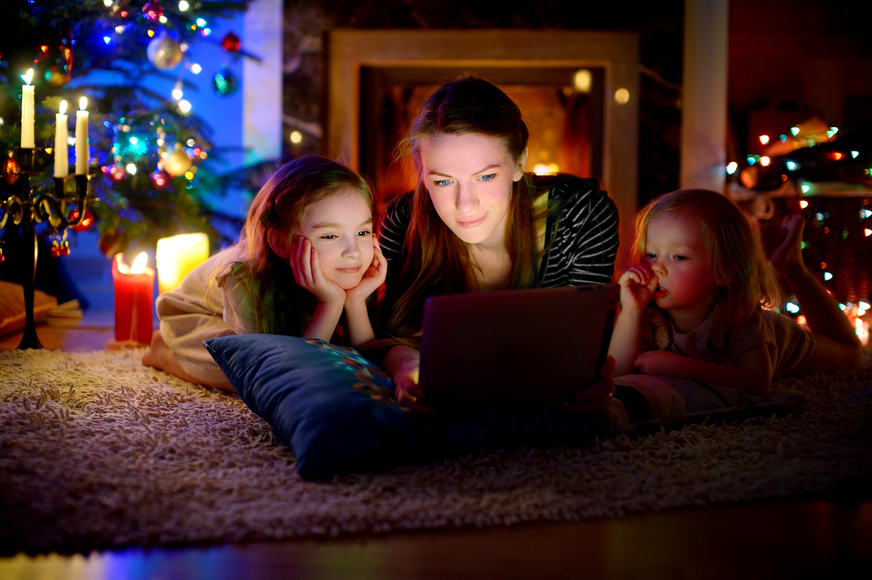 Mother and daughters using tablet by a fireplace on Christmas