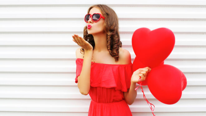 woman blowing kisses and holding heart-shaped balloons