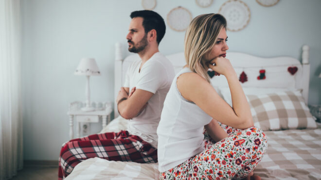 heterosexual couple facing opposite directions on the bed