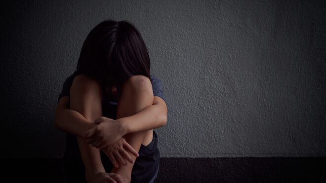 young child alone with head on knees