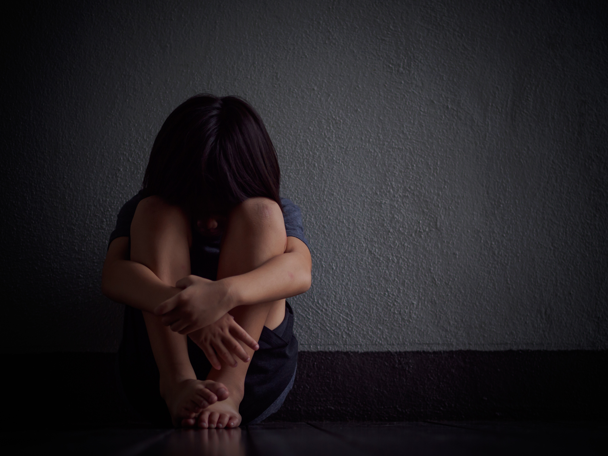 young child alone with head on knees