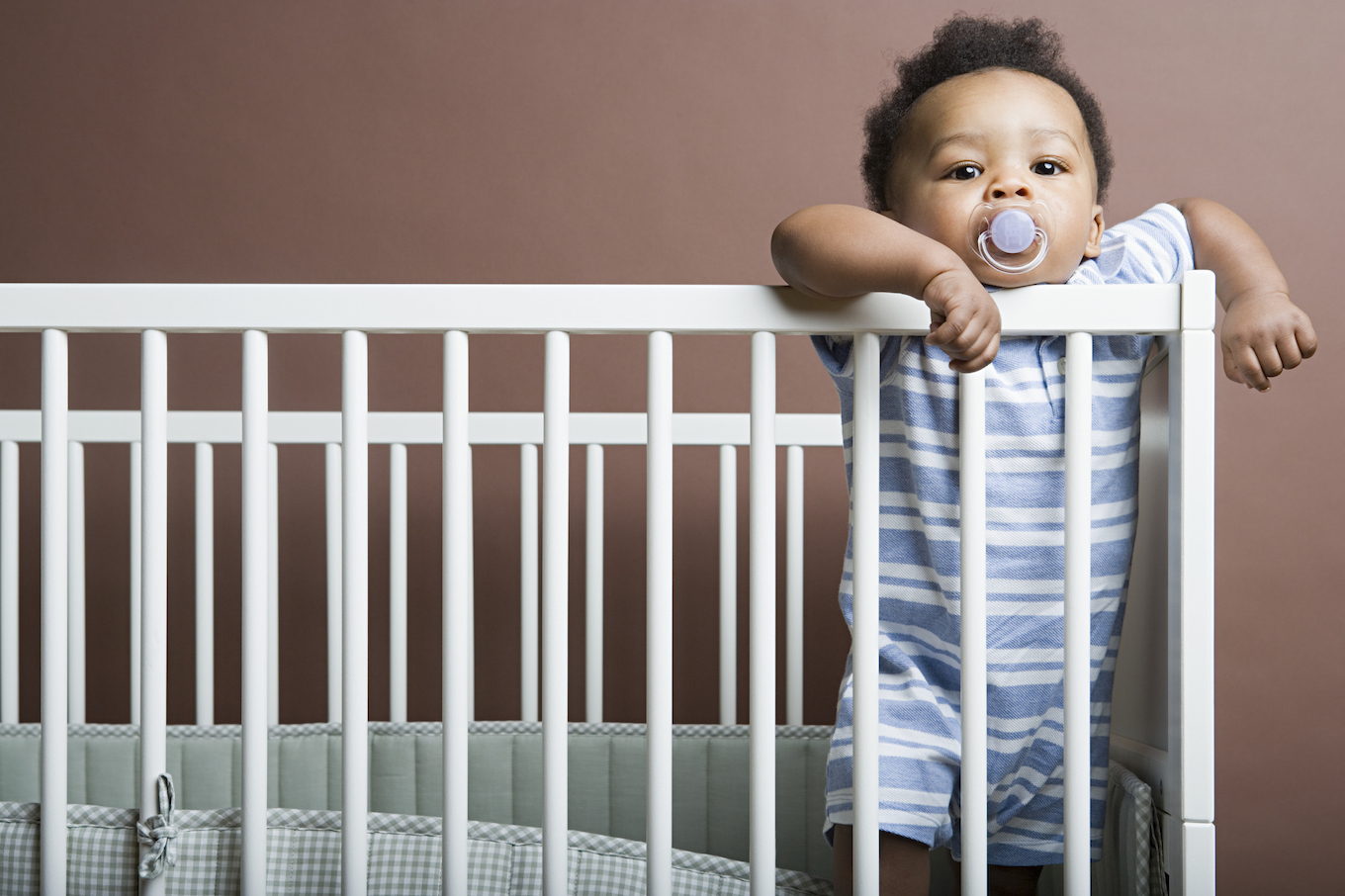 Baby boy standing in cot