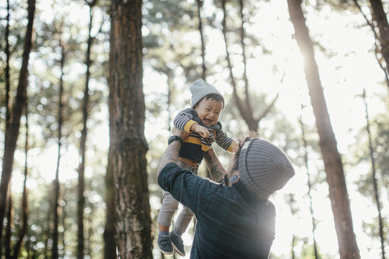 Father holding his son in forest in sunset.