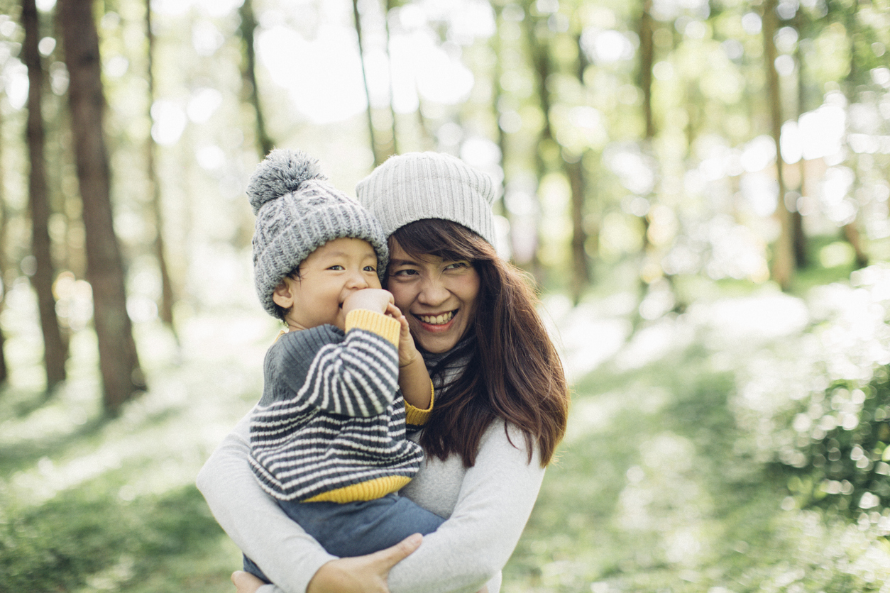 Mother holding his son in forest in morning.