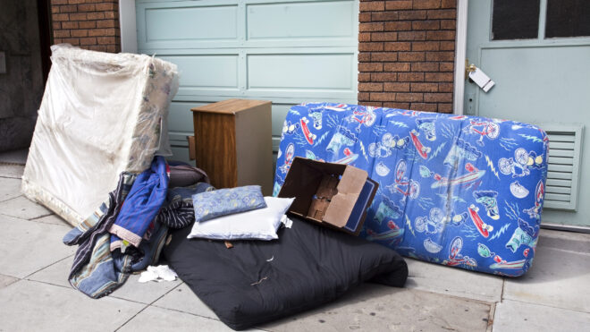 Personal household belongings abandoned on urban sidewalk.