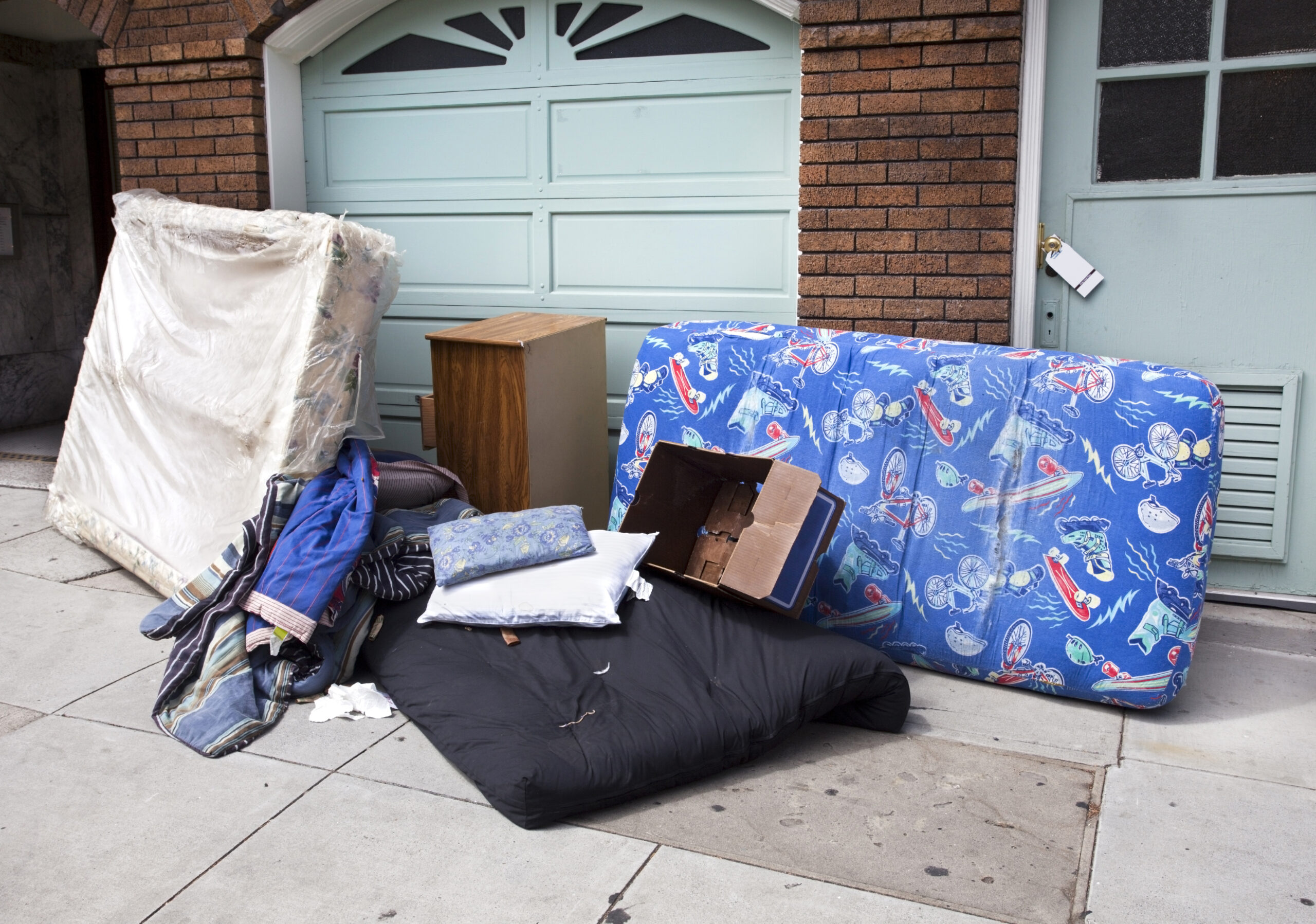 Personal household belongings abandoned on urban sidewalk.