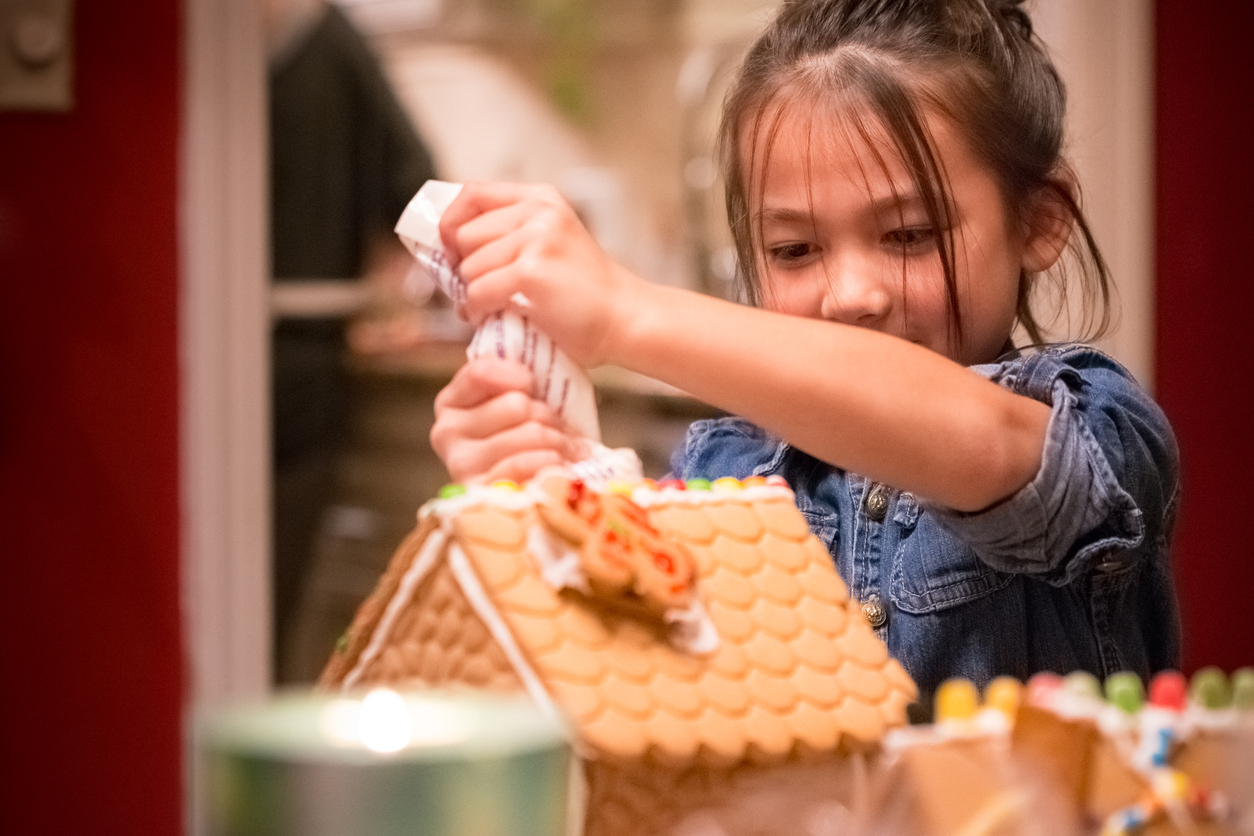Little girl decorating Christmas gingerbread house