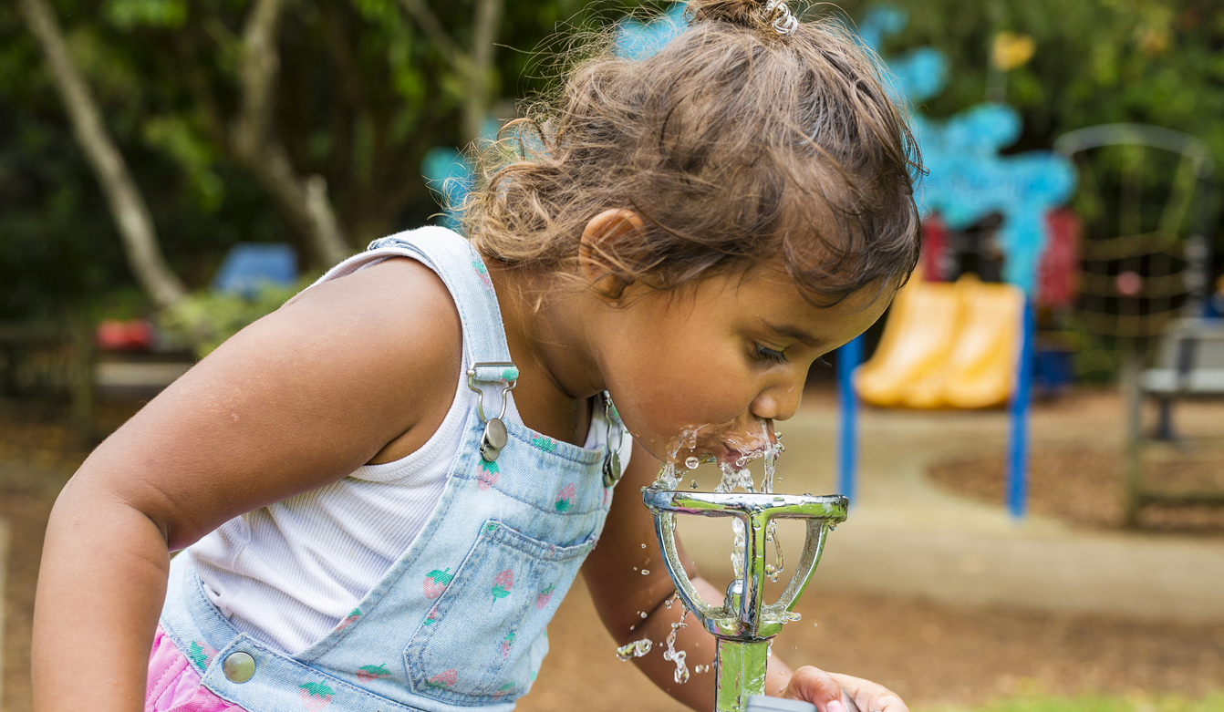 Young Aboriginal Girl Drinking From a Water Fountain