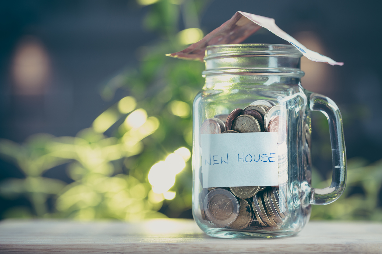 Concept of saving money in a jar on a house.