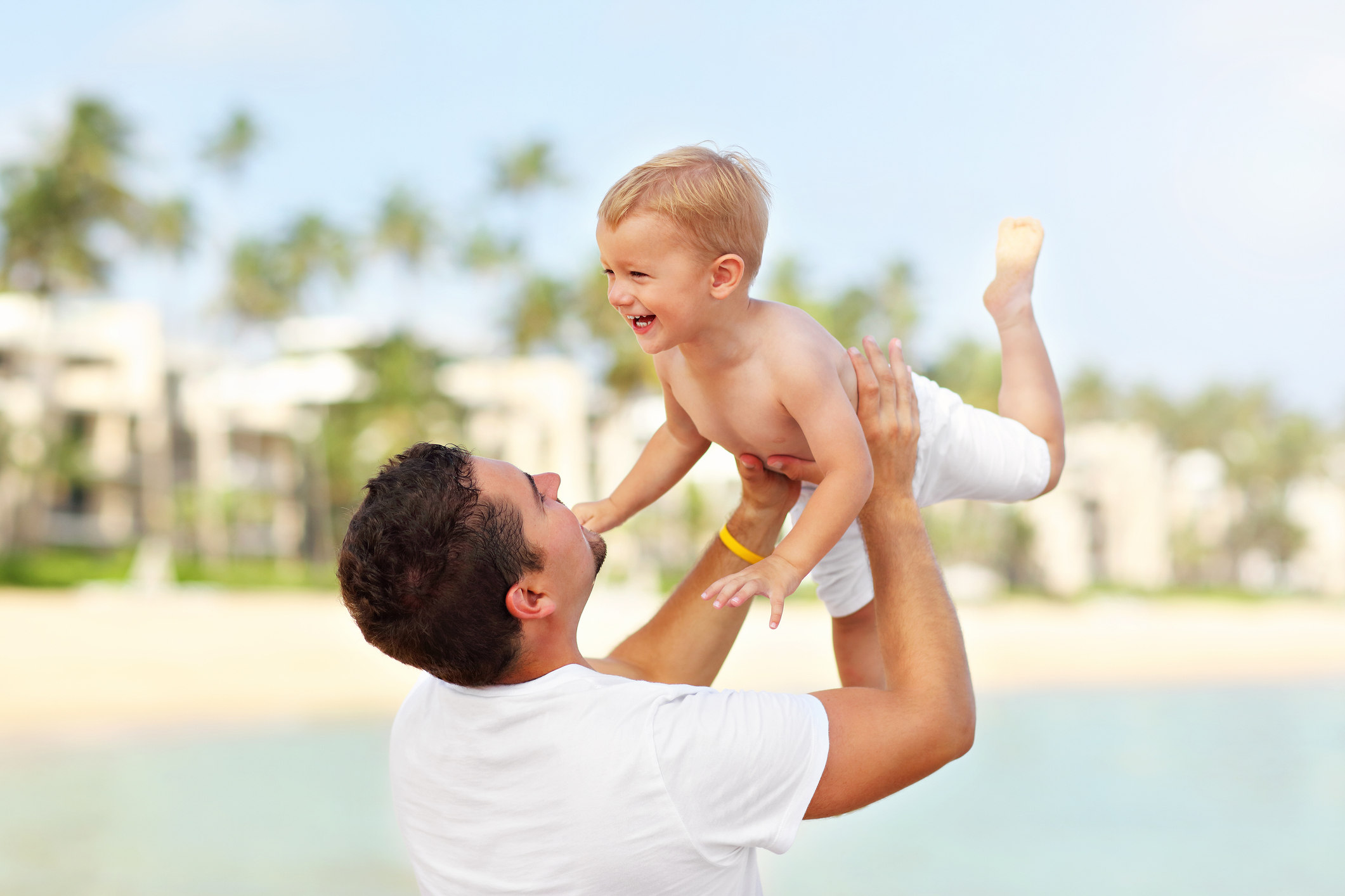 Father having fun on the beach with his little son