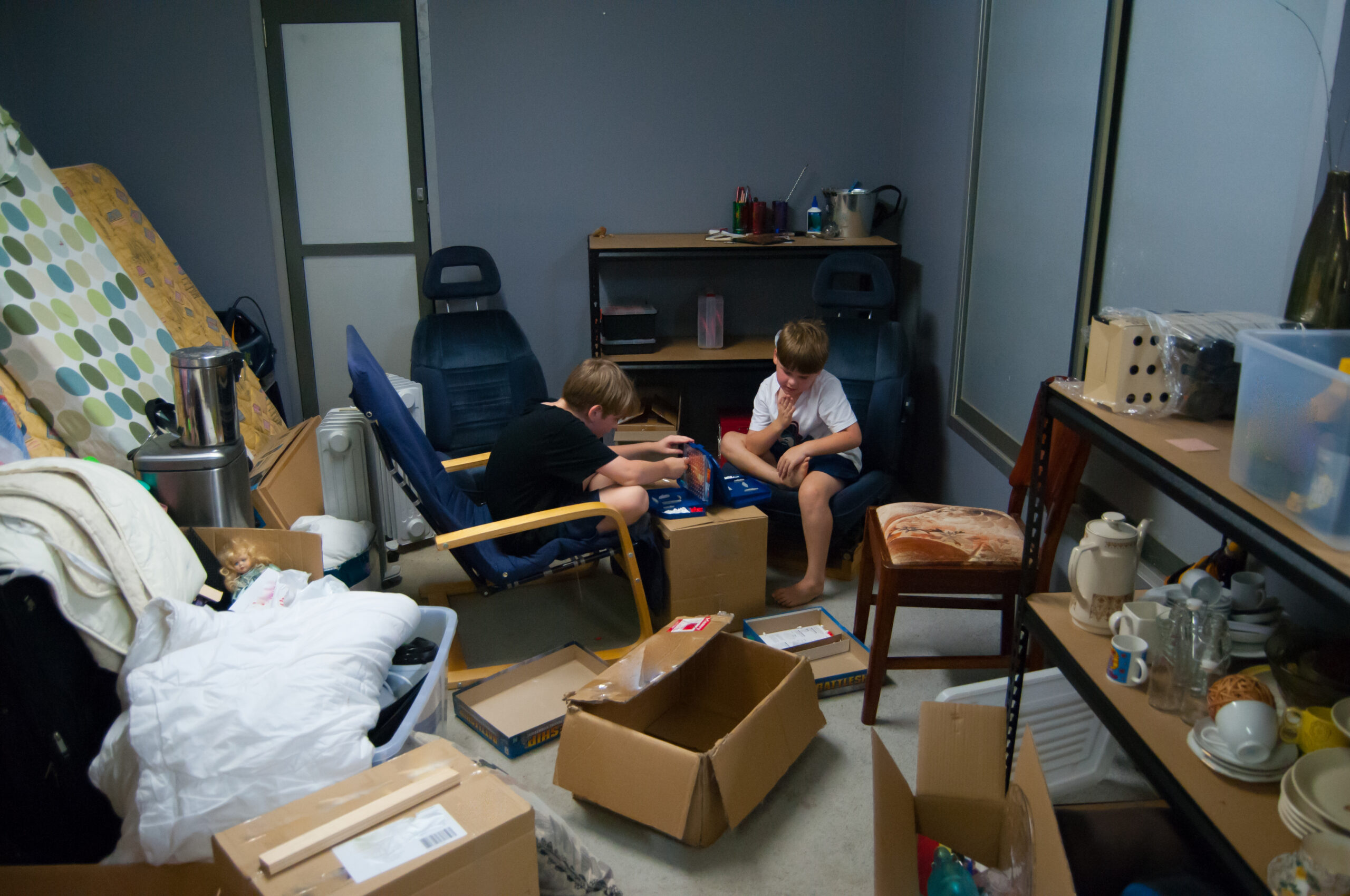 Children playing board game amongst chaos of moving house