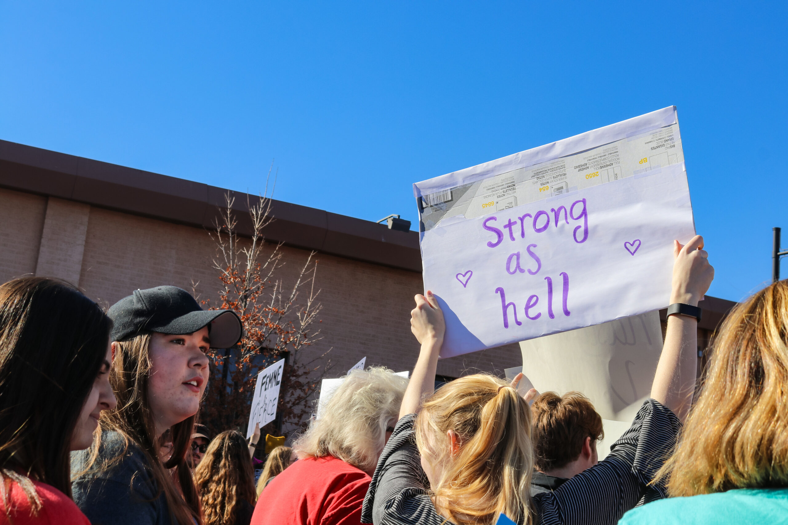 Woman holding sign that says Strong as Hell in Womens March